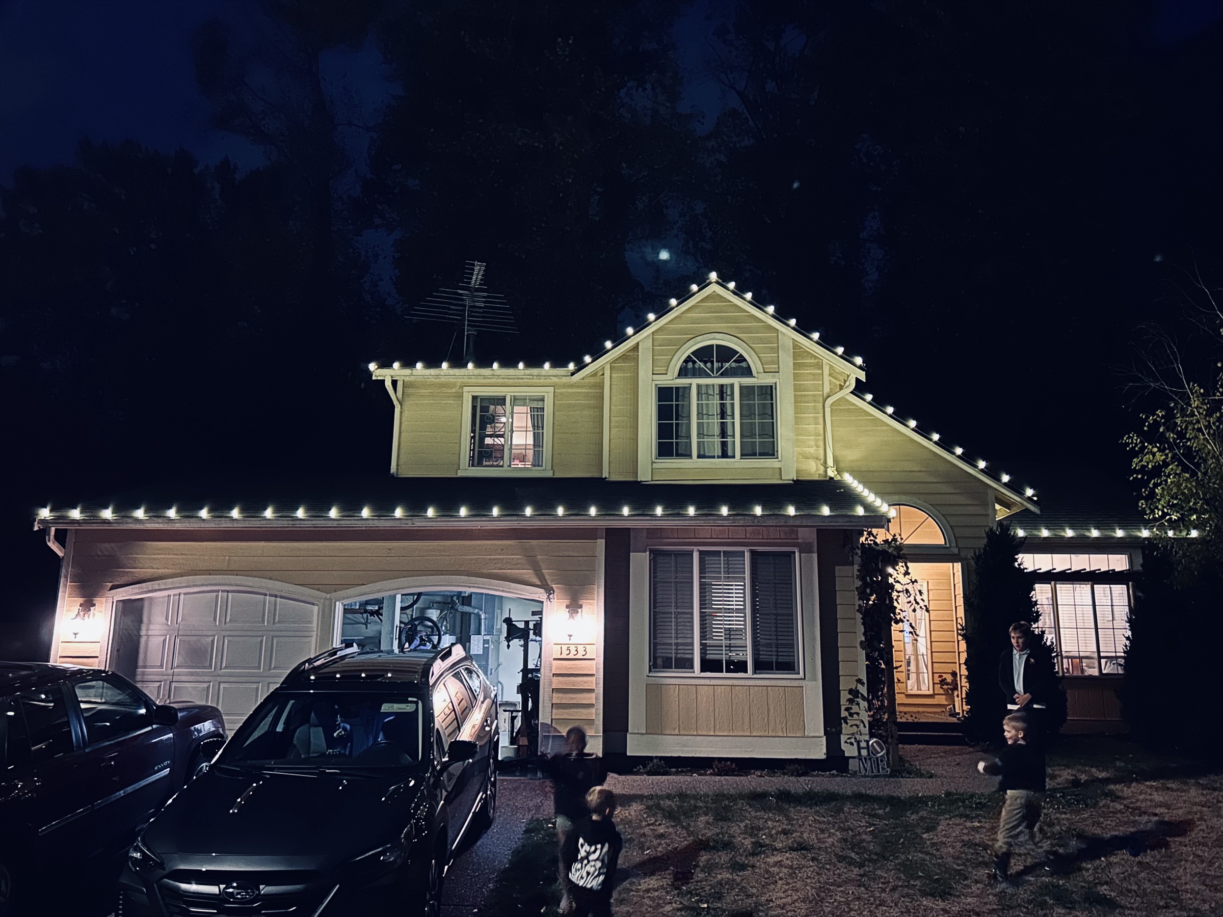 A two-story home outlined in warm white lights